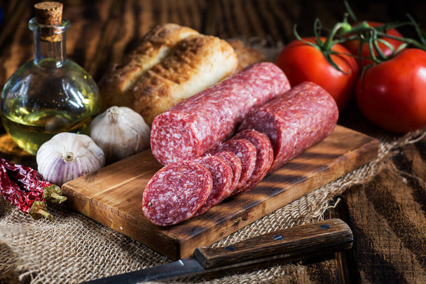 salami slices on a cutting board, bread and garlic on a rustic table. Country style - Foto, immagini