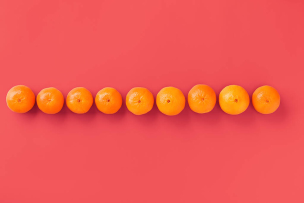 Fruit pattern of fresh orange tangerine or mandarin on living coral background. Flat lay, top view. Pop art design, creative summer concept. Citrus in minimal style. - Foto, immagini