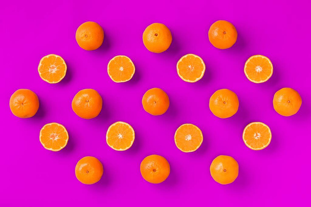 Fruit pattern of fresh orange tangerine or mandarin on lilac background. Flat lay, top view. Pop art design, creative summer concept. Citrus in minimal style. - Foto, Imagem