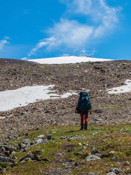 Κάθετη άποψη σόλο πεζοπορία στα βουνά. Ο άντρας με το μεγάλο σακίδιο σκαρφαλώνει σε ένα ορεινό μονοπάτι. Περιπέτεια σόλο ταξιδιωτικό τρόπο ζωής έννοια, ενεργό διακοπές Σαββατοκύριακο στην άγρια φύση - Φωτογραφία, εικόνα