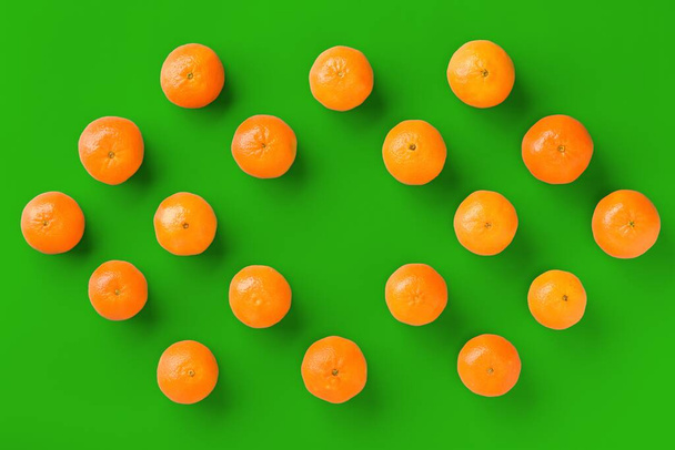 Fruit pattern of fresh orange tangerine or mandarin on green background. Flat lay, top view. Pop art design, creative summer concept. Citrus in minimal style. - Foto, Imagem