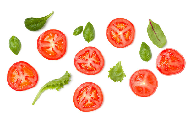 Creative layout made of tomato slices and lettuce salad leaves. Flat lay, top view. Food concept. Vegetables isolated on white background. Food ingredients pattern. - Photo, Image