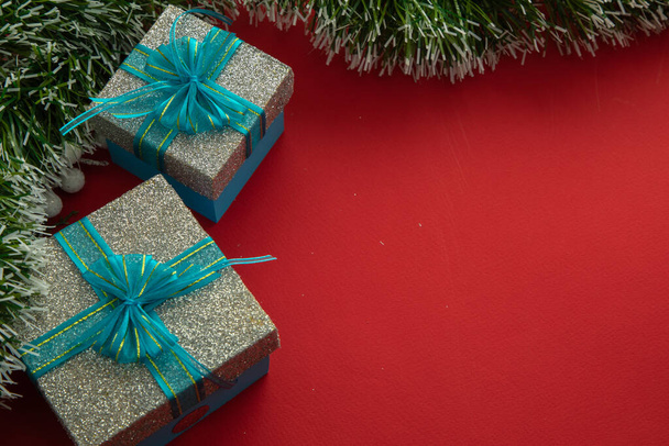 Fondo de Navidad con cajas de regalo con lazo azul, ramas verdes y fondo rojo - Foto, imagen