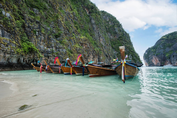熱帯の海と石灰岩の山に囲まれた木製の長い尾のボートの眺めピピ島、ピピ島、タイのクラビ - 写真・画像
