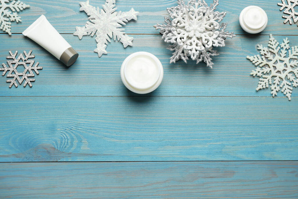 Flat lay composition with cosmetic products and snowflakes on turquoise wooden table, space for text. Winter skin care - Φωτογραφία, εικόνα