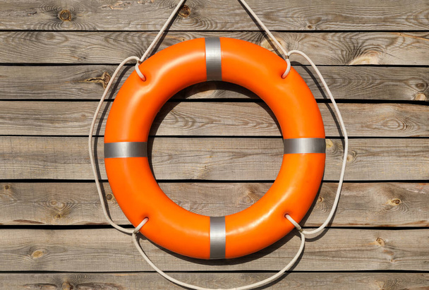 Orange life buoy hanging on wooden wall - Foto, Imagem