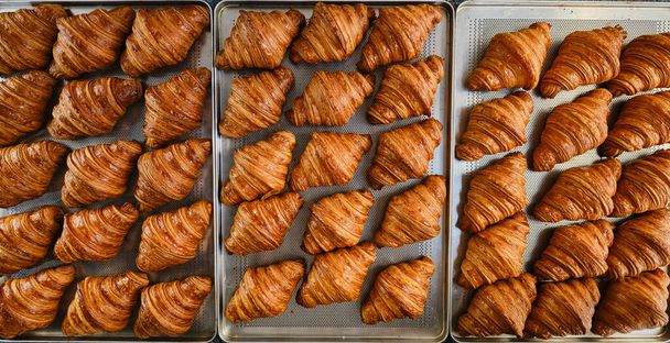 Tuoreita ranskalaisia kultaisia croissantteja leivinpaperilla. Tuoreita klassikoita. Yläkuva  - Valokuva, kuva