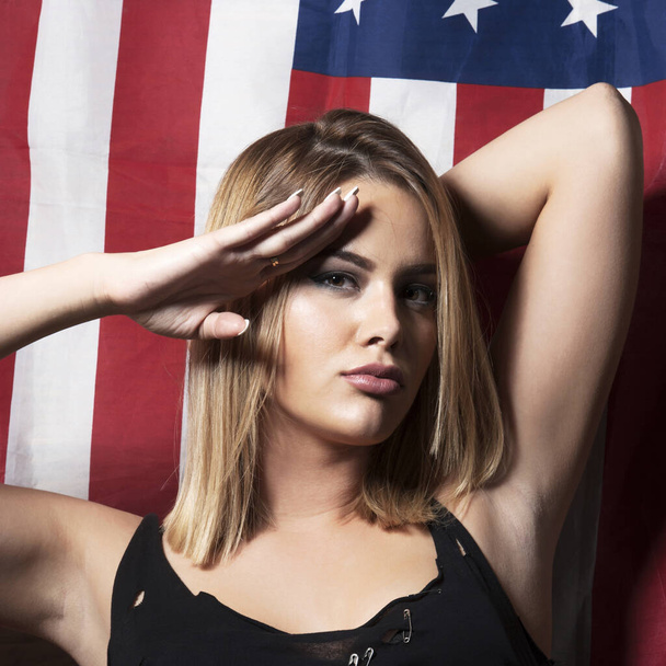 Schöne junge Frau salutiert zur US-Flagge - Foto, Bild