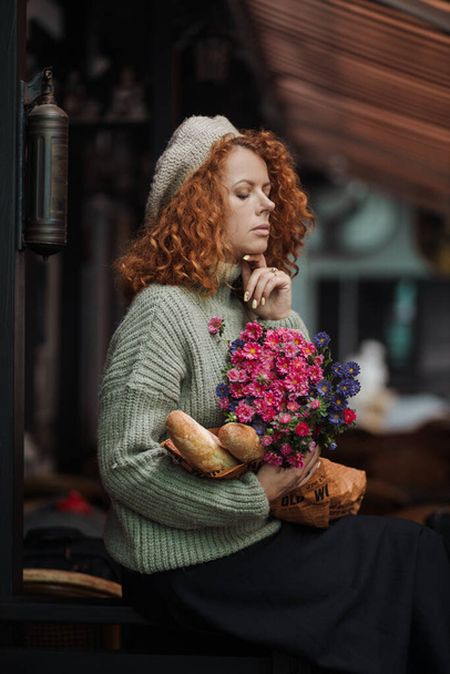 Woman portrait in a beret sweater holding a bouquet of flowers of the restaurant background  - Foto, afbeelding