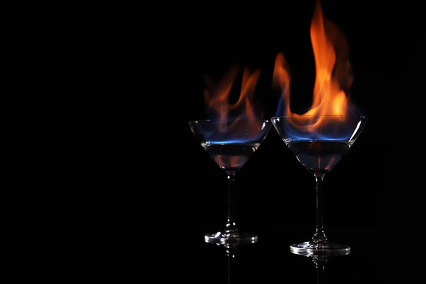 Cocktail glasses with flaming vodka on black background, space for text - Fotoğraf, Görsel