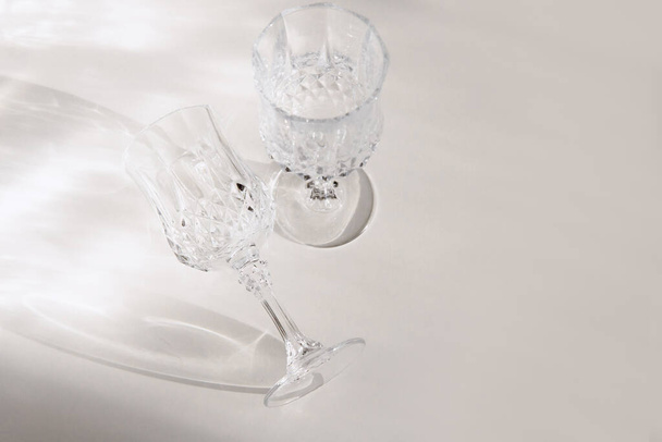 Průhledné sklenice na víno na bílém pozadí, tvrdé světlo a stín. Selektivní soustředění. Autenticita. - Fotografie, Obrázek