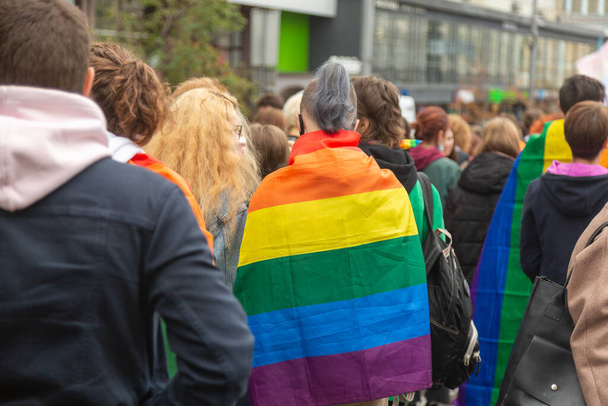 Mensen ondersteunen de LGBTQ gemeenschap tijdens de mars. Regenboogvlaggen op de schouders. - Foto, afbeelding