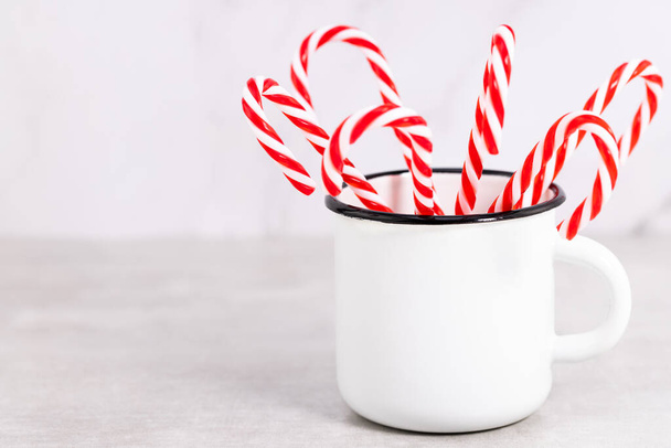 candy cane in a cup on a light background. Christmas background with copy space. - Foto, Imagen