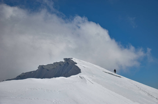 A beautiful shot of a snowy mountain under a cloudy blue sky - Fotó, kép