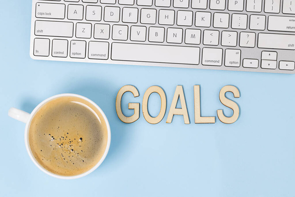 ノートブックでトップビューの目標のビジネスコンセプト,青の背景にコーヒーカップ. - 写真・画像
