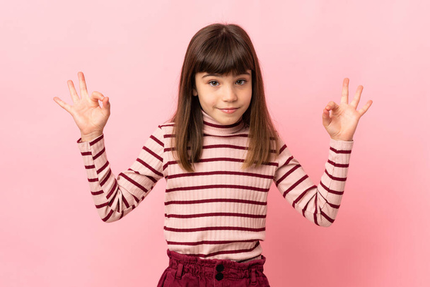 Little girl isolated on pink background in zen pose - Foto, imagen