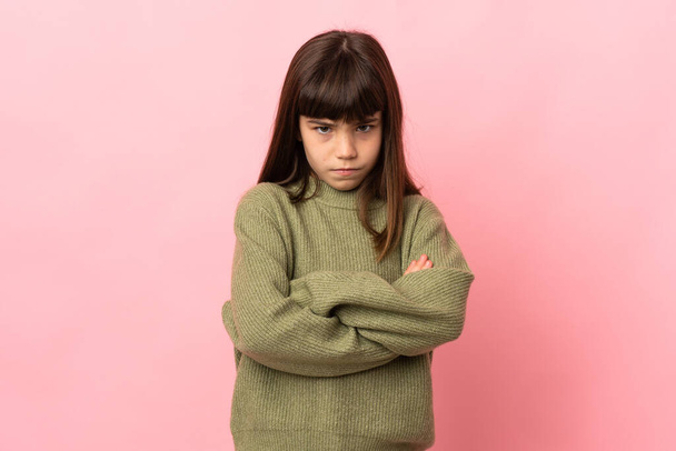 klein meisje geïsoleerd op roze achtergrond met ongelukkige uitdrukking - Foto, afbeelding