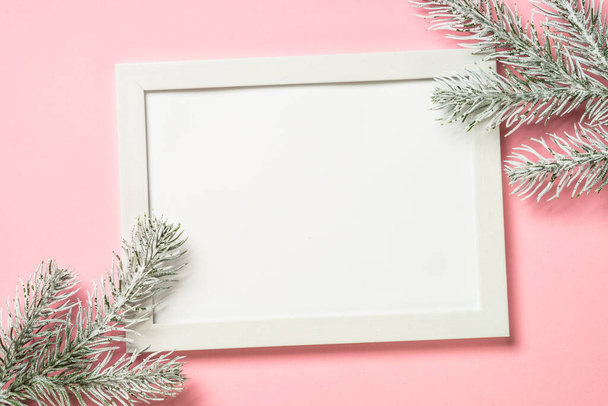 Christmas composition with photo frame and fir tree branch at pink background. - Photo, Image