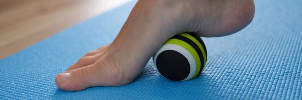 Frauenbein rollt Sportball zur Vorbeugung und Behandlung von Plattfüßen Nahaufnahme - Foto, Bild