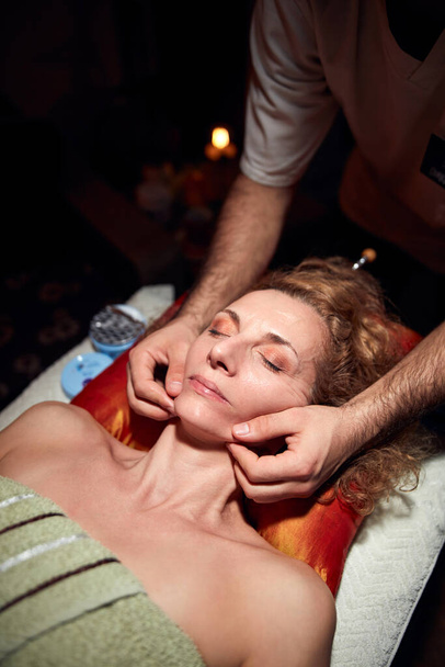 Жінка на масажному, хіропрактичному столі, лікування натягу шкіри тіла та обличчя
. - Фото, зображення
