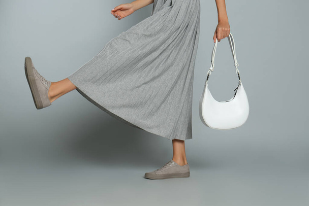 Woman with stylish bag on grey background, closeup - Фото, зображення