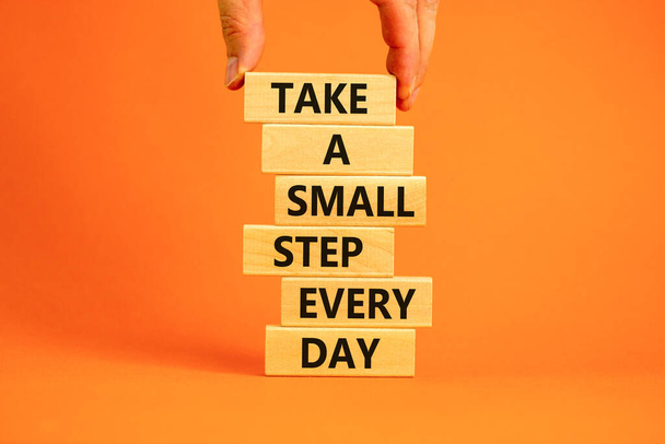 Take a small step every day symbol. Wooden blocks with words Take a small step every day. Beautiful orange background, copy space. Businessman hand. Business, step every day concept. - Photo, Image