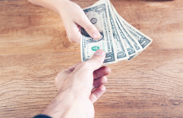 a woman gives dollar bills to a man - Foto, Imagem