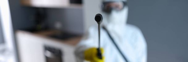 Disinfector in protective suit holding spray with liquid to kill insects closeup - Φωτογραφία, εικόνα
