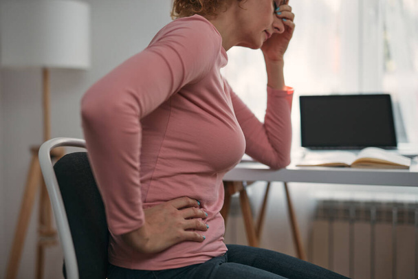 Woman with stomach, hip, spasm, cramp, headache, head pain, working from home troubles and issues. - Foto, Bild