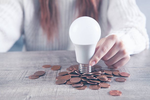holding a light bulb on coins - Foto, imagen