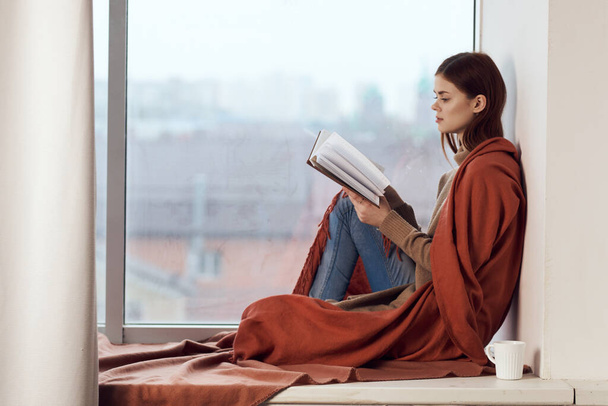woman near the window with a plaid cup of hot drink rest - Zdjęcie, obraz
