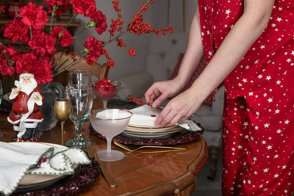 Noel yemeği için yemek masasını peçete ve tabakla hazırlayan, servis yapan ve dekore eden bir kadın. - Fotoğraf, Görsel
