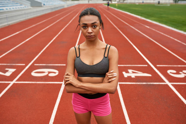 Black sports woman with crossed arms on stadium - Foto, imagen