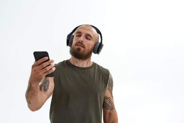Man in headphones watching something on smartphone - Zdjęcie, obraz