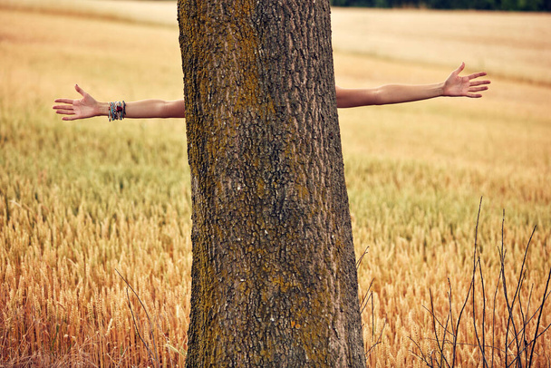Γυναίκα αγκαλιάζει και αγκαλιάζει δέντρο στη φύση. - Φωτογραφία, εικόνα