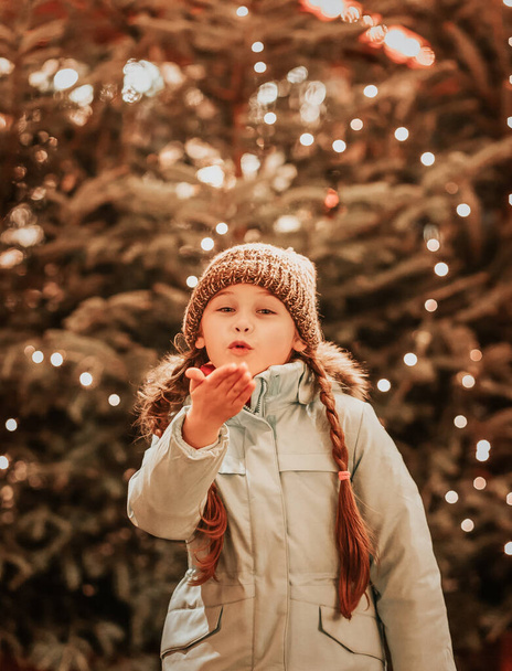 girl and decorating Christmas tree with ornaments outside. Happy - Zdjęcie, obraz