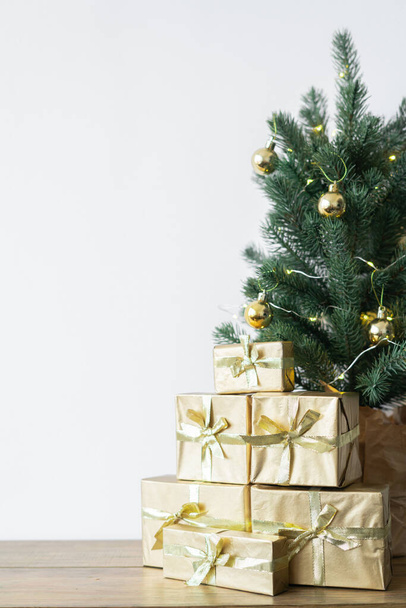 маленька ялинка з теплими цибулинами в горщику на дерев'яному столі з подарунками, загорнутими в золотий папір. концепції Різдва
 - Фото, зображення