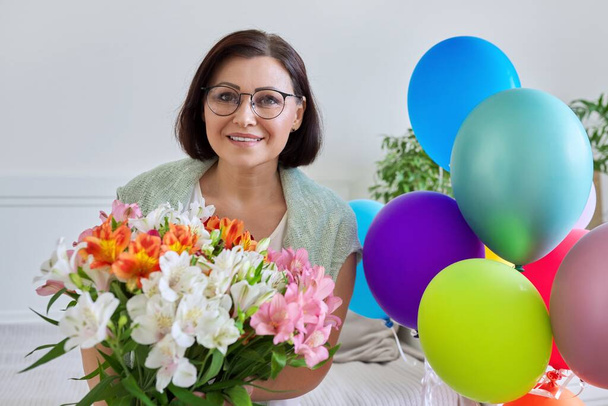 Portrait of middle aged happy woman with bouquet of flowers, balloons - Zdjęcie, obraz