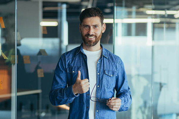 Happy bearded businessman entrepreneur startup owner standing in modern office looking at camera, smiling young hipster, creative man posing in workspace, business portrait - Foto, immagini