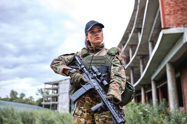 charming confident military lady with weapon in forest, female in camouflage suit - Valokuva, kuva