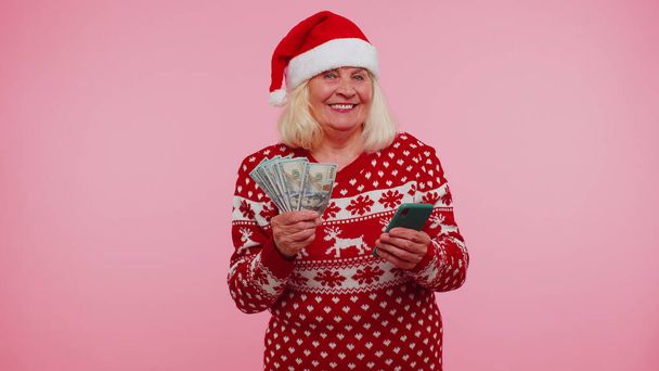 Boże Narodzenie babcia patrząc smartfon szczerze radując wygrać szczęście, otrzymując pieniądze online - Zdjęcie, obraz
