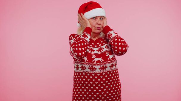 Senior grandmother woman in Christmas clothing covering ears, gesturing no, avoiding advice ignoring - Fotografie, Obrázek