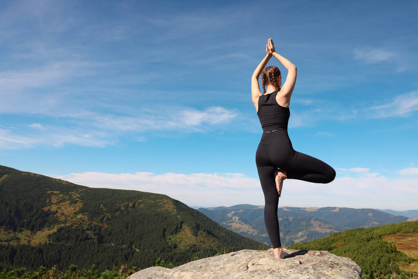 Young woman practicing outdoor yoga in mountains, back view. Fitness lifestyle - Foto, immagini