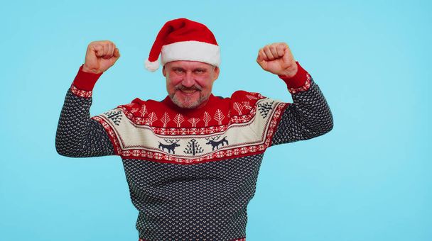 Cheerful man in sweater Christmas Santa shouting, celebrating success, winning, goal achievemen - Photo, Image