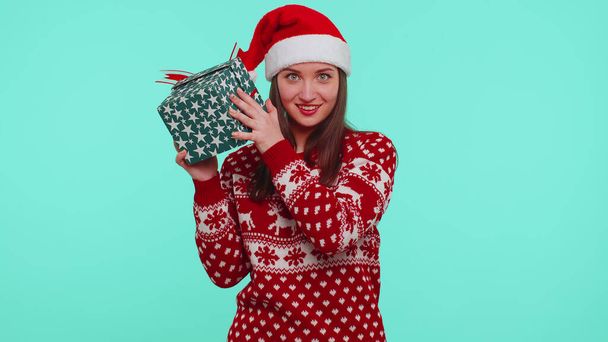 Neşeli kız Noel hediyesi süveteri giyer, hediye kutusuyla ilgilenir. - Fotoğraf, Görsel