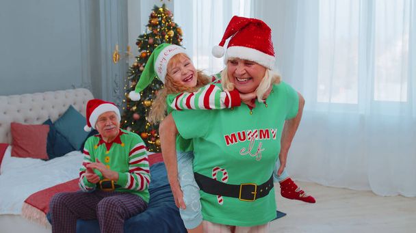 Großmutter trägt kleines Mädchen Kleinkind, spielt Huckepack-Spiel zu Hause Weihnachten Schlafzimmer - Foto, Bild