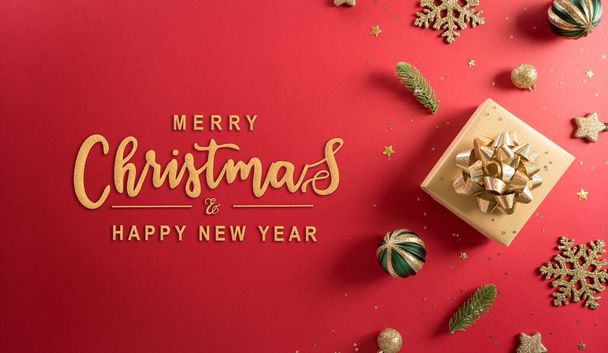 Christmas and new year background concept. Top view of Christmas decoration made from gift box, snowflake, christmas ball and  pine branches on red background. - Photo, Image