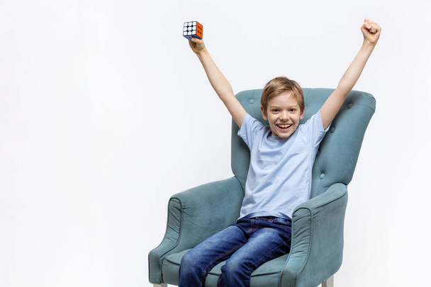 Kyiv, Ukraine, October 9 2021: Young boy holding Rubik's cube and lifting arms with joy. Child expressing happiness after solving mental puzzle. - Foto, imagen