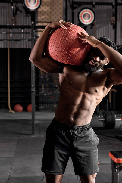 afro american male fitness model exercising with cross fit medicine ball at gym - Valokuva, kuva