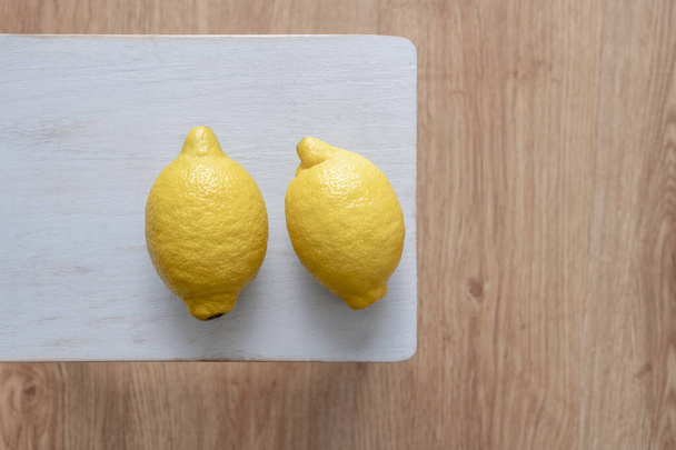 Par de limones amarillos llenos de jugo sobre una mesa azul - Foto, imagen